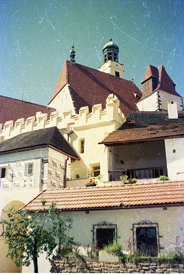 Historic castle complex featuring Gothic Revival architecture with crenellated parapets, steep red-tiled roofs, and decorativ...