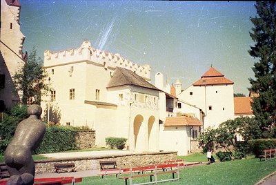 Medieval-style castle with crenellated towers and light beige walls, featuring a mural of stylized hearts on the lower facade...