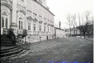 Neoclassical building façade with arched windows and wrought-iron balcony railings, likely from the early 20th century. Grave...