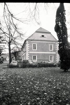 Two-story brick house with gabled roof, symmetrical window placement, and a small dormer. Classic 1950s–1960s European suburb...