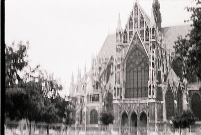 Gothic-style cathedral façade with pointed arches, stained-glass windows, and intricate stonework. Blurred foreground suggest...