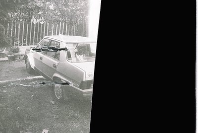Vintage black-and-white photo of a classic sedan parked on uneven terrain, likely post-1960s. Vehicle appears to be a Europea...