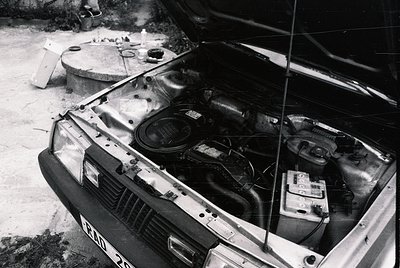 Classic 1970s European sedan engine bay exposed, showing dual carburetors, distributor, and battery. Rust and wear indicate l...