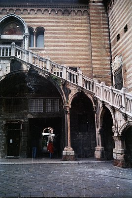 Renaissance-era stone courtyard with arched walkways and spiral staircase in Venice, Italy. Weathered brick walls and intrica...