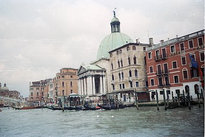 Venetian canal scene featuring the dome of **Santa Maria della Salute** and adjacent historic buildings. Traditional gondolas...