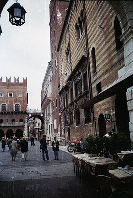 Venetian alleyway showcasing historic brick facades with arched windows and balconies. Cobblestone street lined with outdoor ...