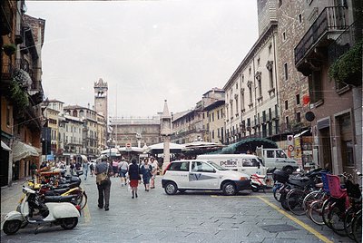 Vibrant 1990s-era street scene in **Bologna, Italy**, showcasing classic medieval architecture with arched doorways and brick...