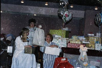Vintage indoor celebration scene featuring three women in 1970s-style attire—one in a white dress, another in a striped apron...