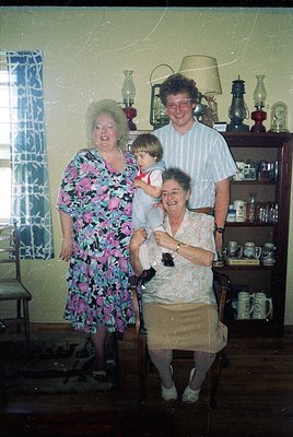 Family portrait in a mid-century kitchen, featuring three adults and a child. The woman on the left wears a floral-patterned ...