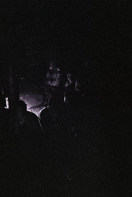 Low-light portrait of a person with blurred facial features, illuminated by a single overhead light source. The silhouette re...