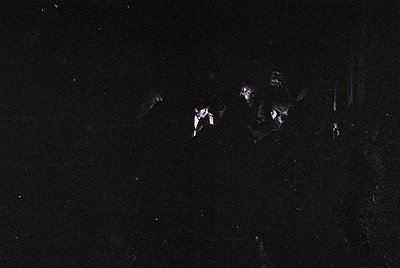 Low-light monochrome shot of three silhouetted figures in motion, likely mid-20th century. Blurred details suggest dynamic ac...