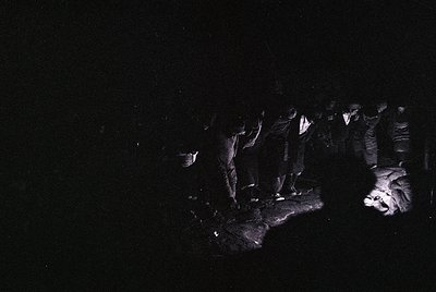 Vintage black-and-white photo of a dimly lit, narrow alleyway with silhouetted figures. Architectural details include arched ...