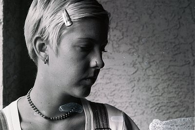 Vintage black-and-white portrait of a young woman with short, side-parted hair and a pearl necklace. She wears a sleeveless b...