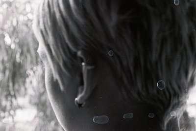 Close-up of a child’s face in motion, captured in monochrome. Soft focus and bokeh effects highlight droplets on the skin, su...