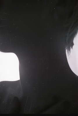 High-contrast black-and-white portrait featuring a close-up of a person’s face partially obscured by a bright light source, c...