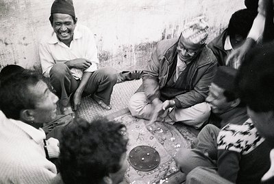 Group of men gathered in a casual, informal setting, likely Nepal, mid-20th century. Traditional attire includes headgear and...