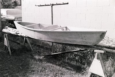 Classic wooden rowboat elevated on supports, likely mid-20th century. Simple, functional design with a single bench seat and ...