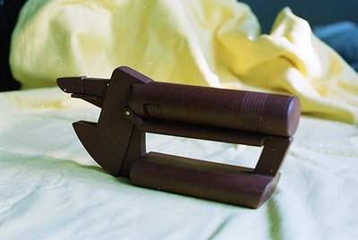 Vintage wooden letter opener with metal tip, resting on a light-colored fabric surface. The design features a curved handle a...