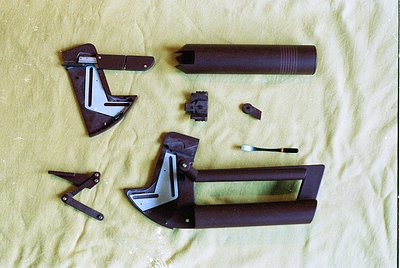 Disassembled vintage metal folding tool set on beige fabric, featuring a cylindrical handle, hinged metal components, and a s...