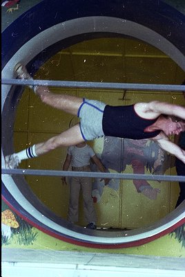 Vintage gymnastic scene through a circular window frame, showing a male athlete mid-dynamic move on parallel bars. White shor...
