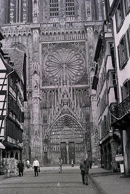Gothic façade of Strasbourg Cathedral’s south portal, flanked by half-timbered medieval buildings. Intricate stone carvings, ...