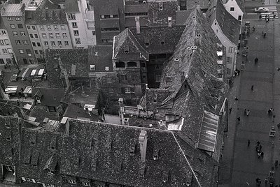Aerial view of densely packed European rooftops, showcasing traditional pitched roofs and chimneys. The architecture suggests...