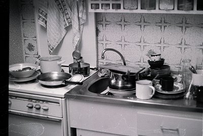 Vintage kitchen sink area with retro stove, faucet, and patterned wall tiles. Mid-century design includes a kettle, coffee po...