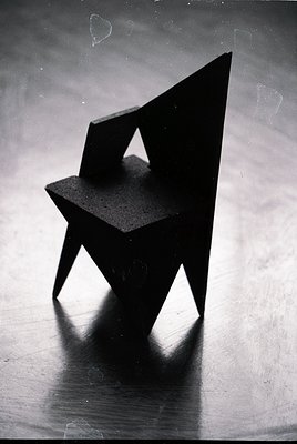 Minimalist geometric chair with angular, floating seat and legs—evoking mid-century modern design. Sharp lines and monochroma...