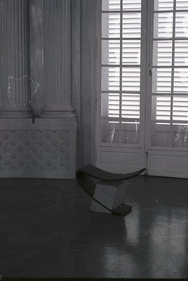 Neoclassical interior featuring fluted columns, ornate plasterwork, and a curved wooden bench against polished marble floorin...