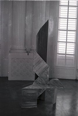 Neoclassical interior featuring geometric marble sculpture and architectural details. The angular, abstract bench contrasts w...