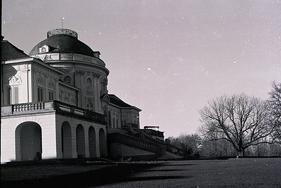 Neoclassical villa with domed roof and arched colonnades, captured in monochrome. Ornate stonework and balustrades highlight ...