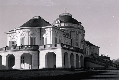 Neoclassical villa with domed roof and arched colonnades, likely 19th-century European architecture. Symmetrical design featu...