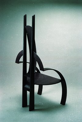 Mid-century modern chair with sculptural wooden frame and curved seat, showcasing organic lines and minimalist design. Likely...