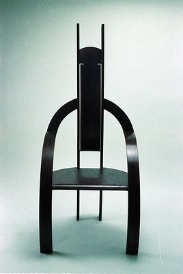 Mid-century modern chair with sculptural wooden legs and curved backrest, likely walnut or teak. Clean lines, minimalist desi...