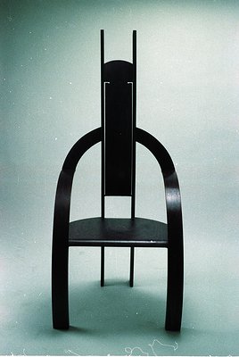 Mid-century modern chair with sleek, curved wooden legs and a minimalist seat. Dark-stained wood contrasts with clean, organi...