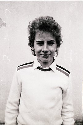 Portrait of a young woman in a vintage sweater with horizontal stripes, likely from the 1960s–1970s. Her curly hair and hoop ...