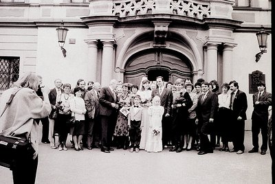 Neoclassical building entrance with arched doorway and decorative stonework hosts a formal gathering. A bride in white stands...