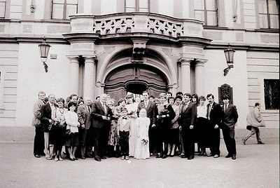 Neoclassical building entrance with arched doorway, flanked by columns and decorative stonework. Group of 18-20 people in 197...