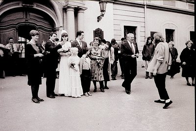 Neoclassical courtyard wedding celebration, 1960s-1970s. Bride in full-length white gown with floral bouquet, surrounded by g...