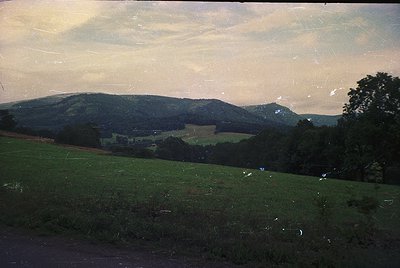 Vintage sepia-toned landscape featuring rolling hills and open fields under a hazy sky. Evidence of slight film damage and fa...