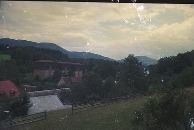 Vintage landscape shot featuring a rustic village nestled in hilly terrain. Mid-20th century architecture with brick building...