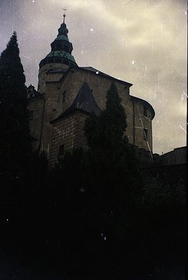 Historic stone church with Gothic Revival architecture—distinctive steep gables, central tower, and green patinated spire. Ov...