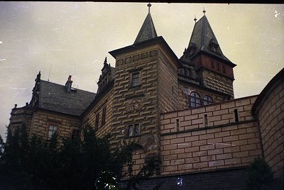 Historic stone building with twin spires and intricate brickwork, likely European . Symmetrical facade features arched window...