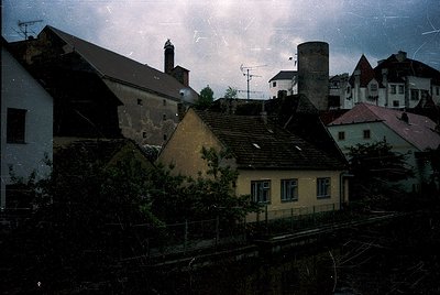Vintage urban rooftops with aged, sloped shingles and chimneys under stormy skies. Mid-20th century European architecture—lik...