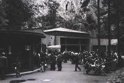 Mid-century urban courtyard with mid-rise building featuring flat roof and minimalist architecture. Crowd of casually dressed...