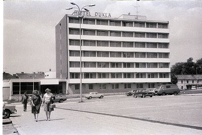 Mid-century concrete hotel facade with "HOTEL DUKLA" sign, likely Eastern Bloc-era architecture. Six-story structure with uni...
