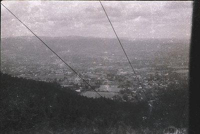 Vintage aerial view of a sprawling urban landscape, likely captured via early 20th-century photography. Dense grid of buildin...