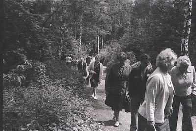 Mid-20th century group hiking on a forested trail, likely 1950s–1960s. Casual attire suggests leisure activity; dense foliage...