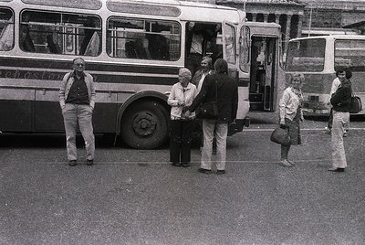 Vintage black-and-white street scene featuring a group of people boarding a mid-20th-century double-decker bus. Urban setting...