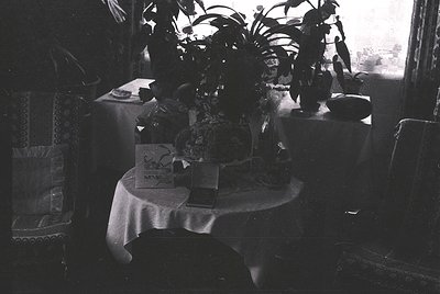 Mid-century dining setup with round table draped in white cloth, surrounded by vintage chairs. Centerpiece features a ceramic...